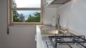 A compact kitchen with a window, stainless steel sink, and gas stove. - Coral Blue by Wonderful Italy (Bellagio)