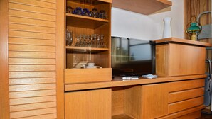 A wooden cabinet with a television, glassware, and a vase. - Coral Blue by Wonderful Italy (Bellagio)