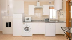 A compact kitchen with white appliances, including a washing machine, dishwasher, and microwave. - Atico Santa Fe in El Puerto de Santa Maria (El Puerto de Santa Maria)