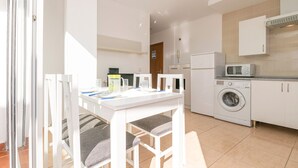 A compact kitchen with a washing machine, microwave, and white cabinets. - Atico Santa Fe in El Puerto de Santa Maria (El Puerto de Santa Maria)