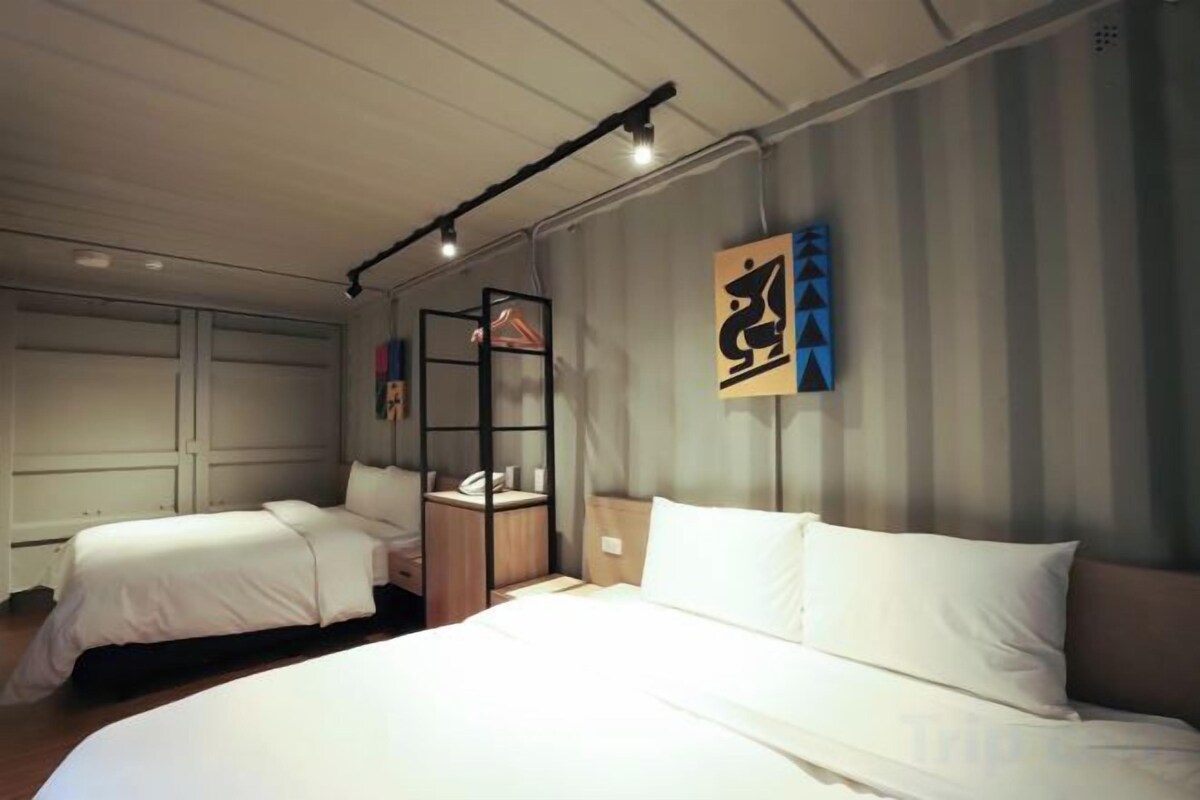 Habitación de hotel con dos camas, un escritorio y un armario.