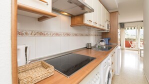 Een moderne keuken met witte kastjes, een houten aanrecht, een ingebouwde kookplaat en een wasmachine.