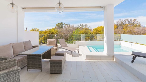 A modern outdoor patio with wicker furniture, a pool, and a clear view of trees. - Artola in Marbella With 4 Bedrooms and 3 Bathrooms (Marbella)