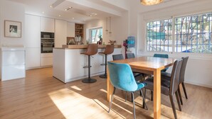 A modern kitchen with white cabinets, a central island, and bar stools. - Axarqu a in Malaga With 2 Bedrooms and 1 Bathrooms (Málaga)