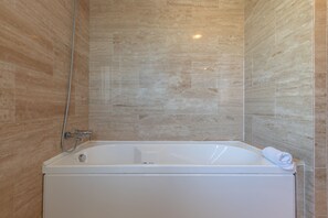 A modern bathroom with a freestanding bathtub, a showerhead, and a towel on the edge. - Bahia Casares 4 in Casares (Casares)