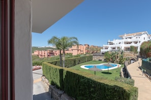 A view of a pool area with a well-manicured lawn, a circular pool, and a palm tree. - Bahia Casares 4 in Casares (Casares)
