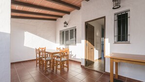 A dining area with a wooden table and chairs, a tiled floor, and a ceiling with wooden beams. - Beautiful Duplex in Chiclana de la Frontera (Chiclana de la Frontera)