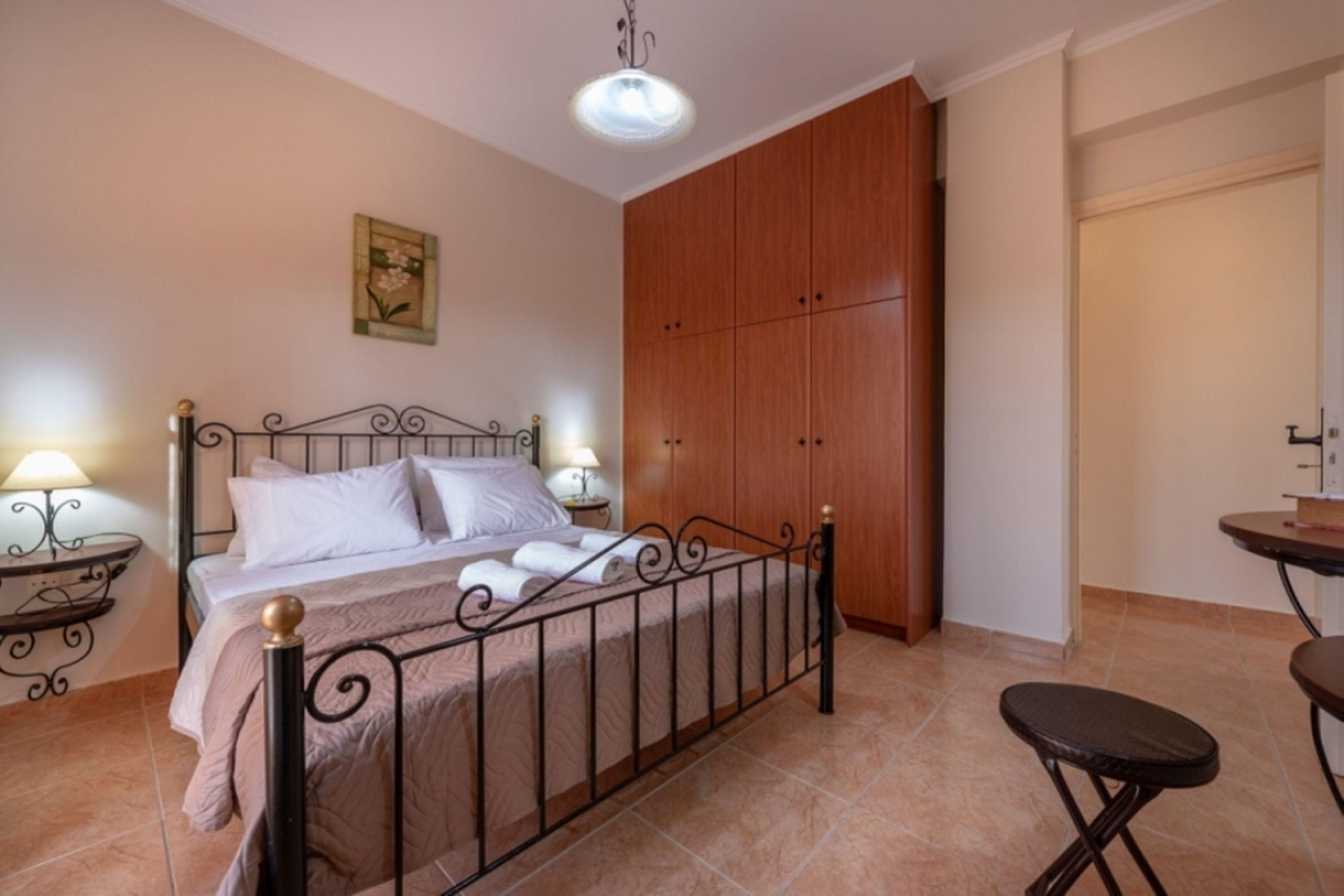Ein Schlafzimmer mit einem Bett, Nachttischen, einem Kleiderschrank und einem kleinen Hocker.