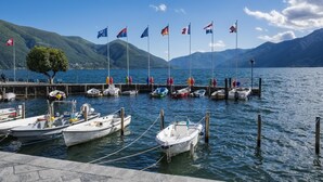 A marina with boats docked, a dock, and a mountainous backdrop. - Red View Apartment in Ronco Sopra Ascona Ascona (Ronco sopra Ascona)