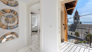 A modern interior with a hallway leading to a balcony with a view of a clock tower. - Red View Apartment in Ronco Sopra Ascona Ascona (Ronco sopra Ascona)