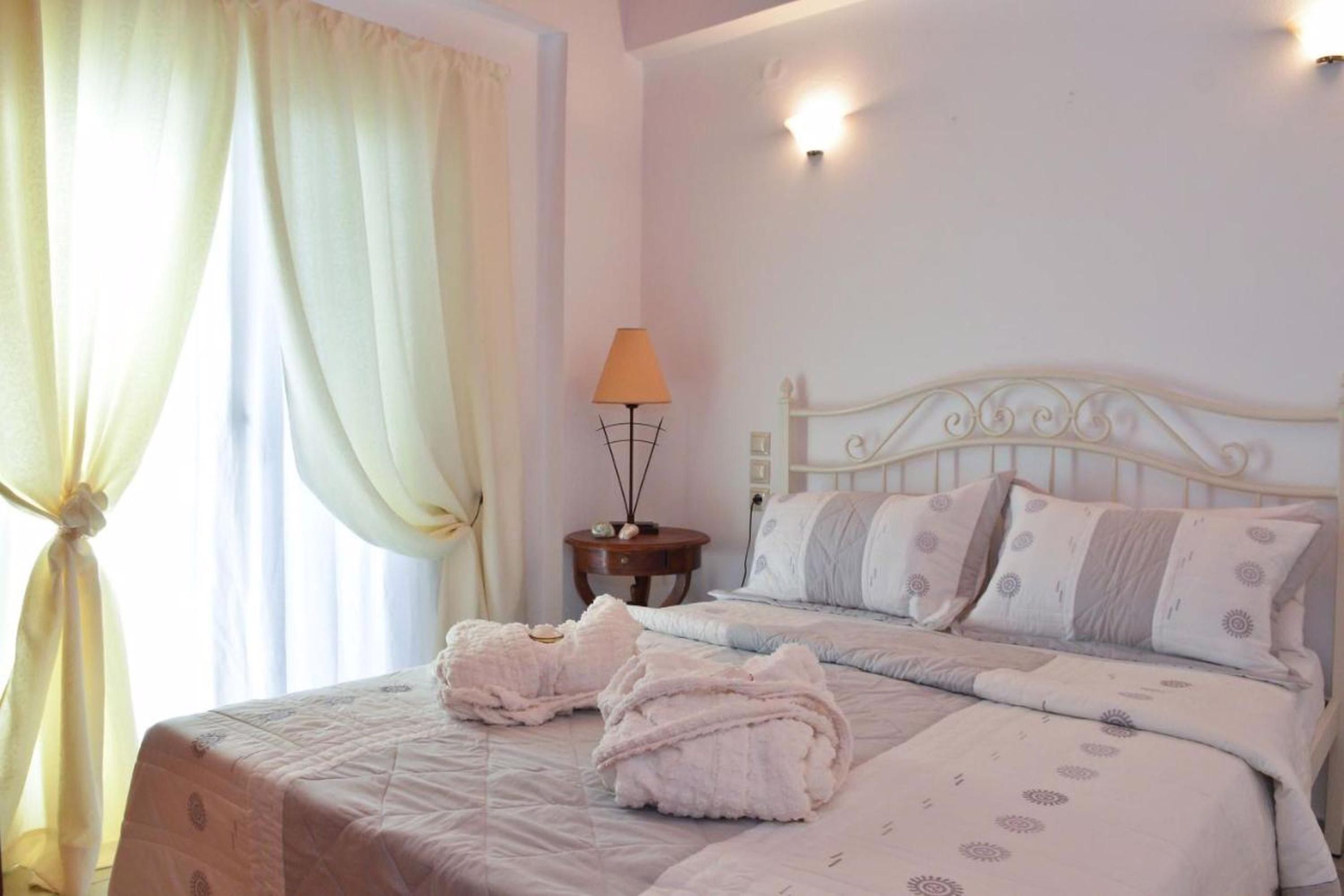 Un lit bien fait, avec une tête de lit blanche, une lampe de chevet et deux serviettes pliées posées sur le lit.