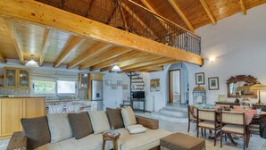 A spacious living area with a high ceiling, wooden beams, a sofa set, a dining table with chairs, and a kitchen in the background. - Villa John Dimeon With Private Pool (West Achaea)