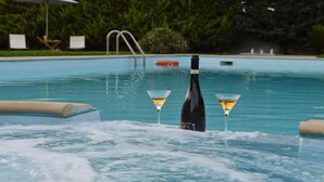 A pool area with lounge chairs and a bottle of wine. - Villa John Dimeon With Private Pool (West Achaea)