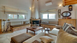A cozy living room with a fireplace, wooden beams, and a comfortable seating area. - Villa John Dimeon With Private Pool (West Achaea)