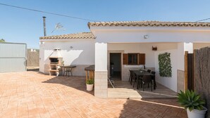 A patio area with a barbecue grill, a dining table, and chairs. - Casa Azul in La Ribera de la Oliva (Barbate)