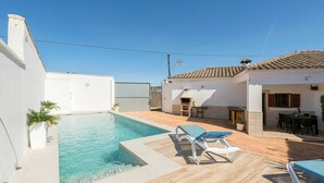 A swimming pool with lounge chairs, a barbecue area, and a patio with a table and chairs. - Casa Azul in La Ribera de la Oliva (Barbate)