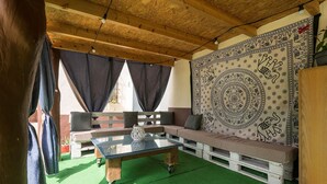 A cozy room with a wooden ceiling, a glass table, a sofa, and a tapestry. - Casa Amelie in Conil de la Frontera (Conil de la Frontera)