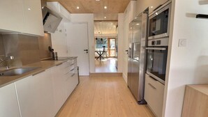 Een moderne keuken met roestvrijstalen apparatuur, houten vloeren en uitzicht op de eetruimte.