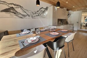 A dining area with a wooden table set for six, surrounded by modern chairs.