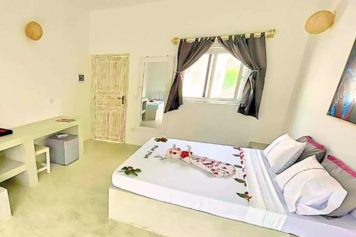 Ein Schlafzimmer mit Bett, Schreibtisch, Stuhl, Kleiderschrank und einem Fenster mit Vorhängen.