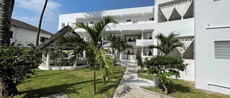 A white building with multiple balconies and a stone pathway.
