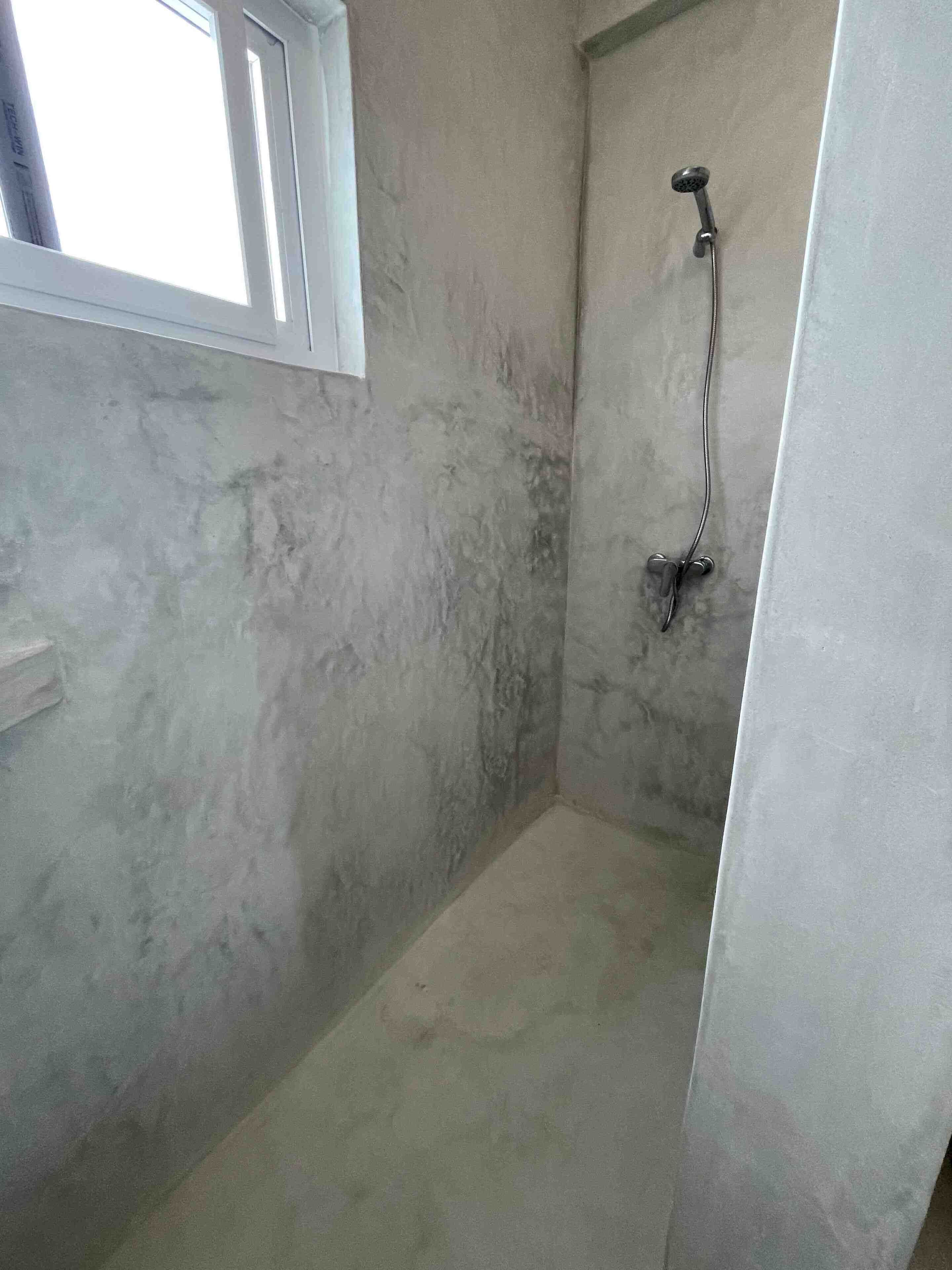 A small, unfinished bathroom with a shower and a window.