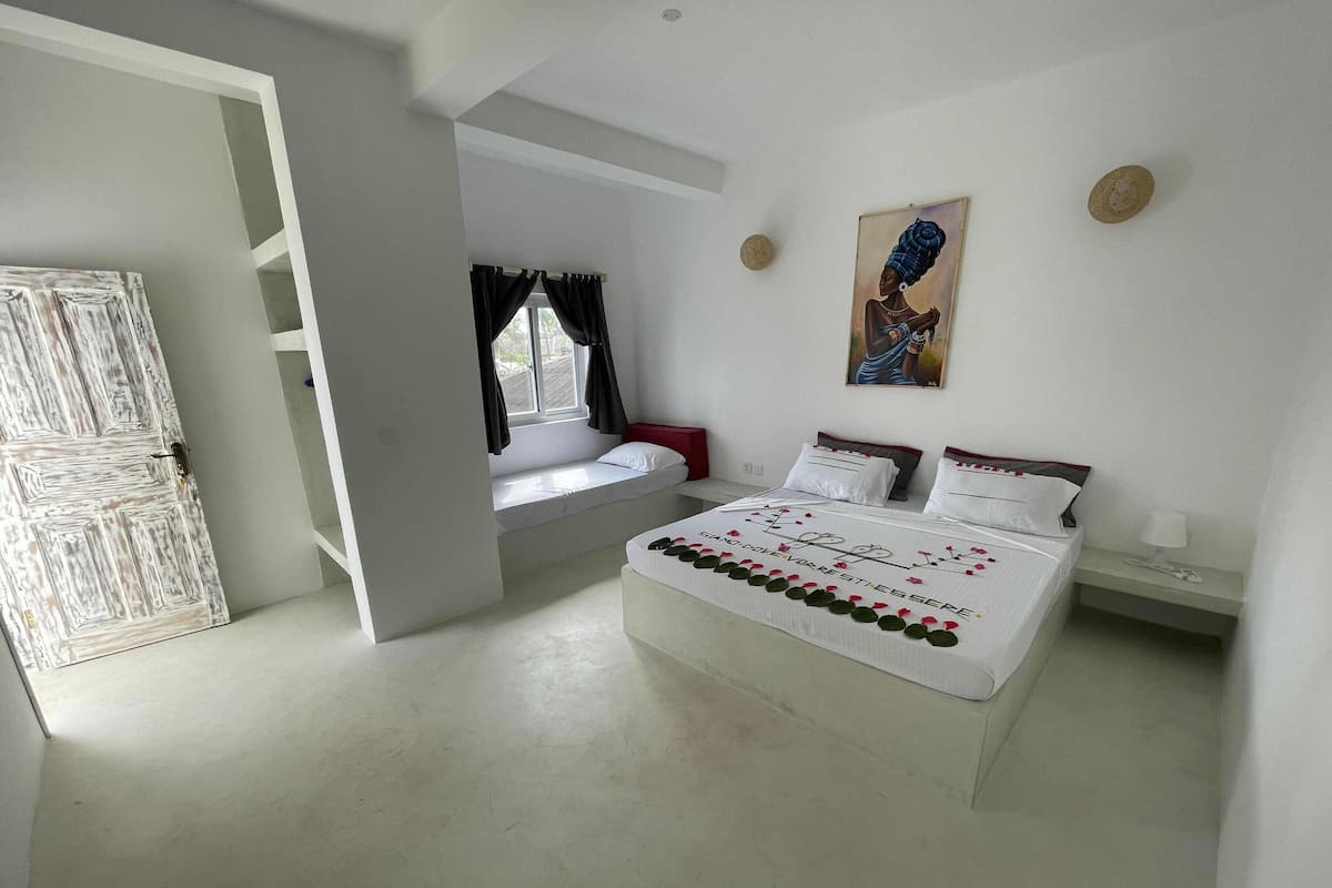 Ein Schlafzimmer mit einem großen Bett, einem Fenster mit Vorhängen, einem Bild an der Wand und einer Tür.