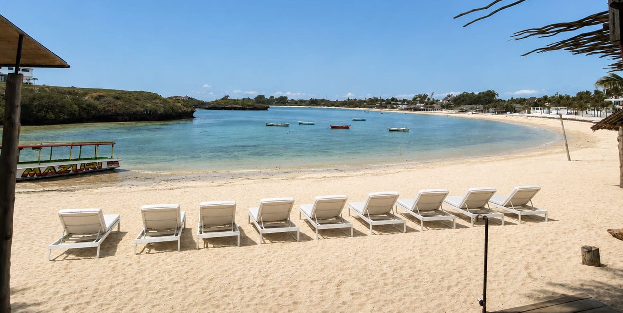 A beach with white lounge chairs and a clear view of the ocean.