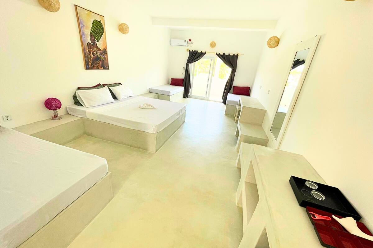 Ein Hotelzimmer mit Bett, Schreibtisch, Stuhl, kleinem Tisch, Spiegel und einem Bild an der Wand.