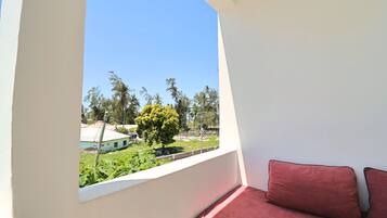A balcony with a view of a garden and a building.