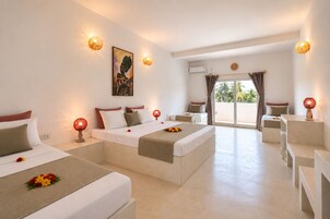 Habitación de hotel con dos camas, un balcón y vistas a palmeras.