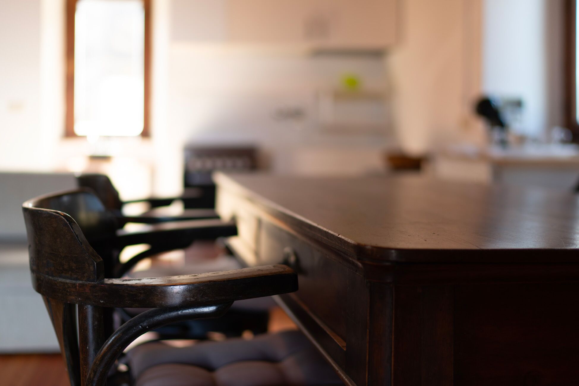 A bar area with a wooden counter and metal chairs.