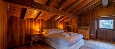 A cozy wooden cabin bedroom with a bed, nightstands, and a window.
