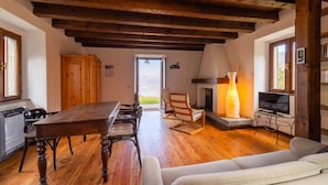 A cozy living room with a wooden table, chairs, a fireplace, and a television. - Baita Gemma by Wonderful Italy (Bellagio)