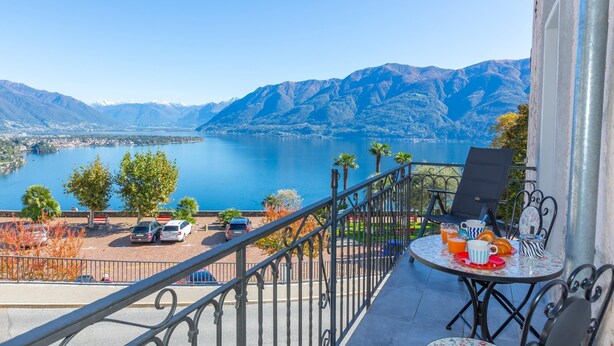 Ein Balkon mit Essplatz, mit Blick auf einen See und Berge.