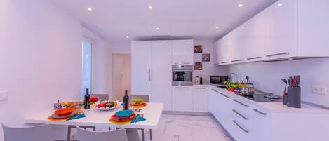 A modern kitchen with white cabinetry, a dining area with a white table, and a small island with a sink and countertop.
