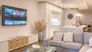 A modern living room with a glass coffee table, a white sofa, and a TV displaying YouTube videos. - Modern Beautifull Pool And Sea Apt Qawra (St. Paul's Bay)