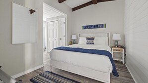 Une chambre à coucher avec un grand lit, une table de chevet, une lampe et un tableau ou une inscription au-dessus du lit.