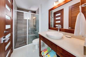 Une salle de bain moderne avec une douche à parois de verre, un lavabo blanc et un meuble-lavabo en bois.