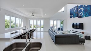 Una cocina moderna con una isla grande, un área de comedor con un sofá y un televisor montado en la pared.