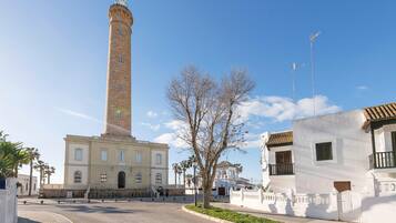 A historic building with a tall tower, a white building with balconies, and a clear blue sky.