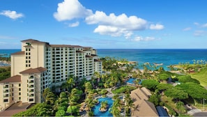 Um resort com um edifício grande, uma piscina e vista para o oceano.