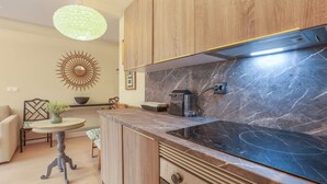 A modern kitchen with a black induction cooktop, wooden cabinets, a marble backsplash, and a unique sunburst wall decoration. - El Alcazar in Sevilla (Seville)