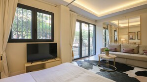 A modern hotel room with a bed, a TV, a sofa, a small round table, and a large mirror. - El Alcazar in Sevilla (Seville)