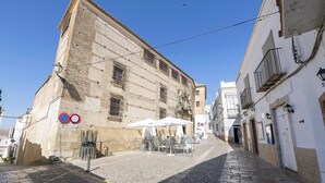 A cobblestone street with a building featuring a white facade and a balcony. - Casa Cuna in Arcos de la Frontera (Arcos de la Frontera)