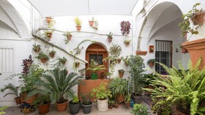 A courtyard with various potted plants arranged around a central doorway, surrounded by white walls and arches. - Casa Cuna in Arcos de la Frontera (Arcos de la Frontera)