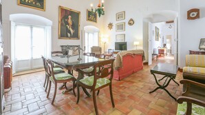 Un vaste salon comprenant un coin repas, avec une grande table à manger en bois, plusieurs chaises, un canapé et un téléviseur.