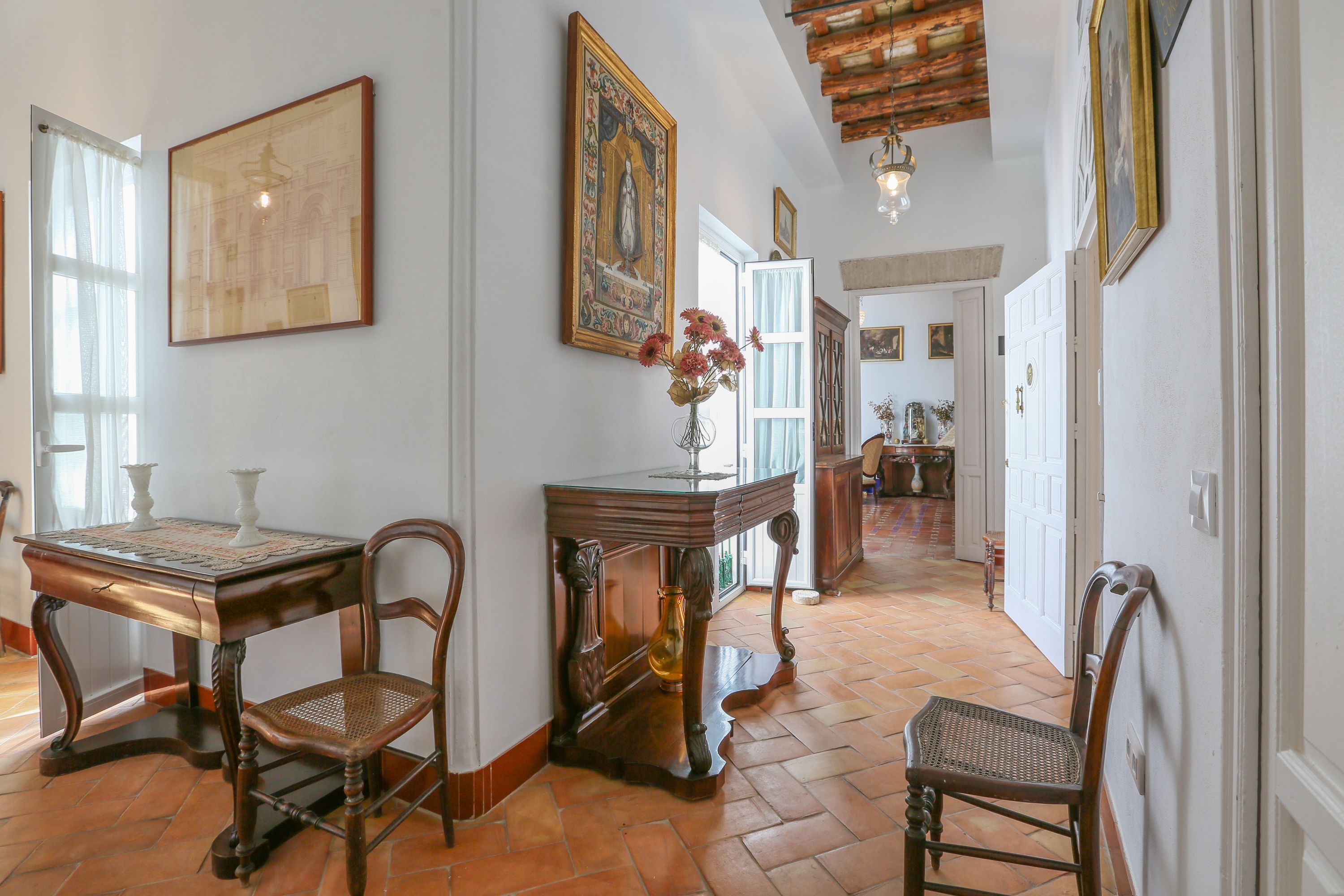 A traditional interior with a wooden table, chairs, and a vase with flowers.