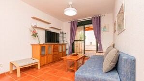 A compact living space with a sofa, a small wooden table, a bench, and a cabinet. - Oasis Playero in Chiclana de la Frontera (Chiclana de la Frontera)