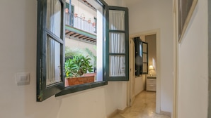 Ein Flur mit einem Fenster, das auf einen Balkon mit Blumentöpfen hinausführt.